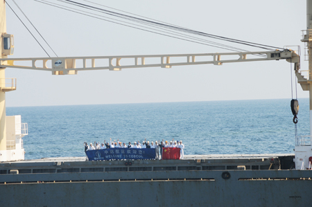 Crew members on the merchant vessel &apos;Lemin&apos; hold Chinese national flag and a banner to welcome the Chinese navy fleet which will escort it to pass through the Gulf of Aden, on February 1, 2009. The Chinese naval fleet started carrying out the 15th batch of escort missions against pirates February 1.