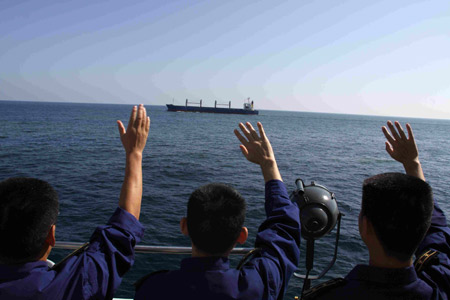 Chinese navy soldiers on Chinese destroyer Wuhan wave to a merchant vessel as they escort it to pass through the Gulf of Aden, on February 1, 2009. The Chinese naval fleet started carrying out the 15th batch of escort missions against pirates February 1.