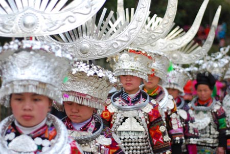 A group of ethnic Miao's young women in splendid silver headwears dance to the rhythm and beat of folk dancing of Lusheng (a reed-pipe Bamboo-cluster flute), in a brisk celebration of the lunar Spring Festival, at Nanqing Village, Danzhai County, southwest China's Guizhou Province, on January 31, 2009.