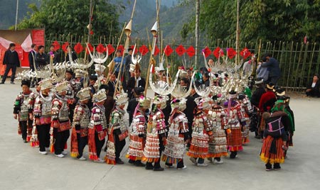 A group of ethnic Miao's young women in splendid silver garbs dance to the rhythm and beat of folk dancing of Lusheng (a reed-pipe Bamboo-cluster flute), in a brisk celebration of the lunar Spring Festival, at Nanqing Village, Danzhai County, southwest China's Guizhou Province, on January 31, 2009.