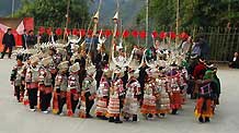 A group of ethnic Miao's young women in splendid silver garbs dance to the rhythm and beat of folk dancing of Lusheng (a reed-pipe Bamboo-cluster flute), in a brisk celebration of the lunar Spring Festival, at Nanqing Village, Danzhai County, southwest China's Guizhou Province, on January 31, 2009.