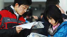 Jobseekers browse brochure of job information at a job fair held in Yantai, east China's Shandong Province, on February 3, 2009.