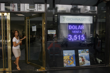 A woman walks past an electronic board showing the exchange rate between US dollars and Argentina Peso on February 4, 2009. The exchange rate between US dollars and Argentina Peso on Wednesday is US$1 to 3.51 Argentina Pesos, the highest ever since the end of 2002. [Xinhua]