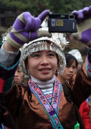 A girl of Miao ethnic group takes picture in the Hongshui Village of Rongshui Miao Autonomous County, southwest China's Guangxi Zhuang Autonomous Region, on February 4, 2009, the Spring Begins, first of the 24 solar terms in China's lunar calendar. Residents of Miao ethnic group celebrated the Begin of Spring by various activities, such as Lusheng (a reed-pipe Bamboo-cluster flute) Dance and Lusheng blowing on Wednesday. 