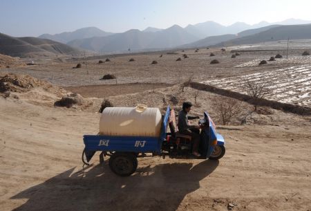 Farmer He Baojian steers a tractor to carry drinking water in Taiping township of Huining County, northwest China's Gansu Province, on February 5, 2009. The county has suffered from serious drought since September 2008 with about 150,667 hektares of farmland and 184,000 people and 326,000 livestocks short of water. 