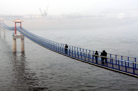 Tourists walk on an iron-chain bridge near the outlet of the Xiaolangdi Dam on the Yellow River in central China's Henan Province, on February 5, 2009. The Yellow River Flood Control and Drought Relief Headquarters has launched an orange alert for grim drought situation on Tuesday. The daily average water flow through the Xiaolangdi Dam was increased to 600 cubic meters per second to help soothe the drought in areas along the Yellow River. 