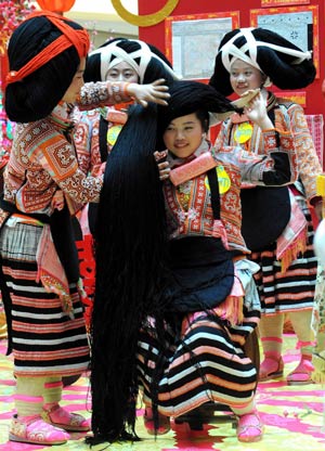 Girls of an old branch of the Miao ethnic group from southwest China's Guizhou Province help comb hair for their companion to form a unique hair style like ox's horn in south China's Hong Kong, on February 5, 2009.