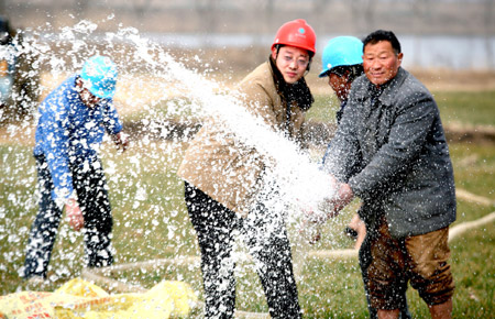 Workers of a power company help a farmer to irrigate the field in Wuhe County, east China's Anhui Province, on February 5, 2009.