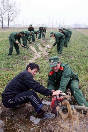 Soldiers of armed police force help a farmer to irrigate his field in Huainan, east China's Anhui Province, on February 5, 2009.