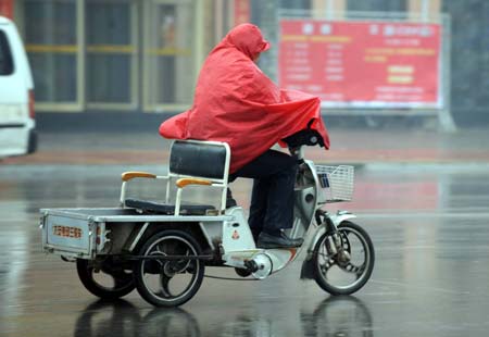 A resident rides a tricycle in rain in Heze, a city in east China's Shandong Province, on February 8, 2009. A rainfall hit some areas of Shandong, partially easing the ongoing drought plaguing province.