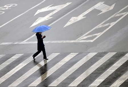 A resident walks in rain on Ma'anshan Road in Jinan, capital city of east China's Shandong Province, on February 8, 2009. A rainfall hit some areas of Shandong, partially easing the ongoing drought plaguing province.