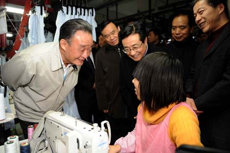 Wu Bangguo (L), chairman of the Standing Committee of China's National People's Congress (NPC), who is also a member of the Standing Committee of the Political Bureau of the Communist Party of China Central Committee, talks with a worker at Youngor Group in Ningbo, east China's Zhejiang Province, on February 5, 2009. Wu paid an investigation tour to Zhejiang Province from February 5 through 9.