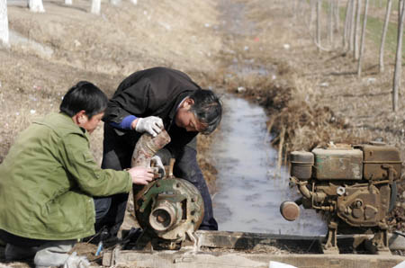 Farmers fix water pump in Fuchun Township in Heze City, east China's Shandong Province, on February 10, 2009. Thirty floodgates are opened in Shandong Province to draw water from the Yellow River to irrigate the wheat fields in fighting against the drought and reducing damages. 