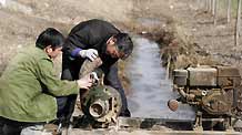Farmers fix water pump in Fuchun Township in Heze City, east China's Shandong Province, on February 10, 2009. Thirty floodgates are opened in Shandong Province to draw water from the Yellow River to irrigate the wheat fields in fighting against the drought and reducing damages.