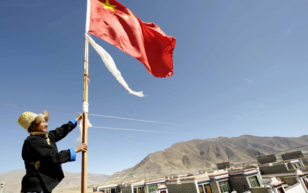 A Tibetan villager fixes a flagstaff with Chinese national flag next to his new house in Kunggar Town of Maizhokunggar County in Lhasa, capital of southwest China's Tibet Autonomous Region, on February 11, 2009. 
