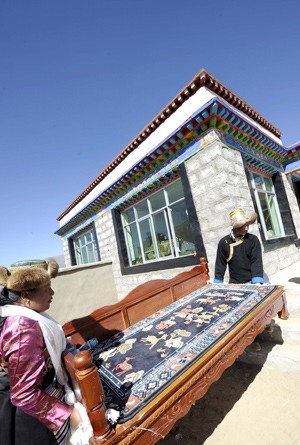 Tibetan villagers carry a piece of furniture into their new house in Kunggar Town of Maizhokunggar County in Lhasa, capital of southwest China's Tibet Autonomous Region, on February 11, 2009.