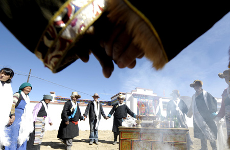 Tibetan villagers dance during a celebration for moving into new houses in Kunggar Town of Maizhokunggar County in Lhasa, capital of southwest China's Tibet Autonomous Region, on February 11, 2009.