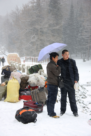 Two men wait for coach in the snow in Hami, northwest China's Xinjiang Ugyur Autonomous Region, on February 11, 2009. The light to moderate snow fall hit the north Hami along the Tianshan Mountains which relieved the drought in Barkol Grassland. 