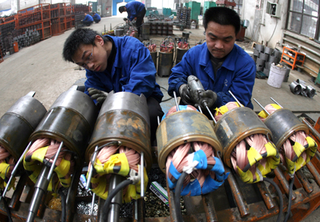 Workers fix electric pump machines in the workshop of a pump company in Yuncheng, north China's Shanxi Province, on February 12, 2009.