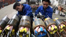 Workers fix electric pump machines in the workshop of a pump company in Yuncheng, north China's Shanxi Province, on February 12, 2009.