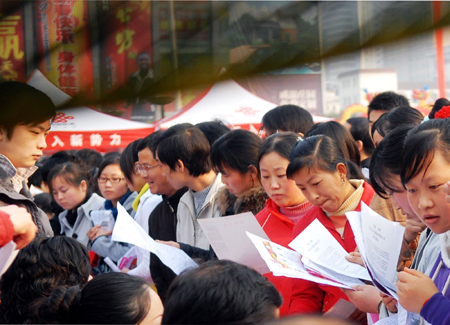 Migrant workers consult on a job fair in Yichang, central China&apos;s Hubei Province, on February 12, 2009. 