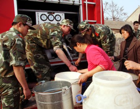 Soldiers help the villagers to get water from a fire engine in Lieshan Township in Huaibei City, east China's Anhui Province, Feb. 12, 2009. Fire engines were sent to deliver water for residents in the villages of Lieshan Township. Huaibei city has suffered from drought since October last year. (Xinhua/Wan Shanchao)(