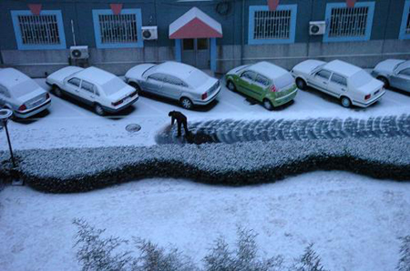 A resident living in Shijingshan district clears snow on the road in Beijing, capital of China, on February 17, 2009. Beijing welcomes its first snow after the Spring Festival. 