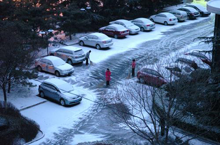 Residents living in Shijingshan district clear snow on the road in Beijing, capital of China, on February 17, 2009. 