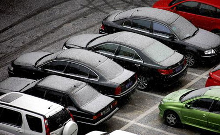 Cars covered by snow park alongside a road in Beijing, capital of China, on February 17, 2009. 