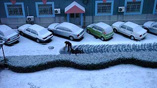 A resident living in Shijingshan district clears snow on the road in Beijing, capital of China, on February 17, 2009. Beijing welcomes its first snow after the Spring Festival.