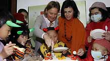 Ms. Cathleen Pecsteen (L), wife of the Consul General Mr. Marc Pecsteen of the Consulate General of the Kingdom of Belgium in Shanghai, and Judit Hajba (R), the culture attache of the Hungarian Consulate in Shanghai, cut the cake with leukemia-afflicted kids, at Tongji Hospital in Shanghai, east China's metropolis, on February 17, 2009. Foreign friends are invited to the Shanghai Tongji Hospital for a theme amicable activity of Lightening the Endeared Aspiration with Charitable Hearts, henceby handing out donations and love-heart gifts to the leukemia-afflicted children and show heartfelt wishes for their convalescence.