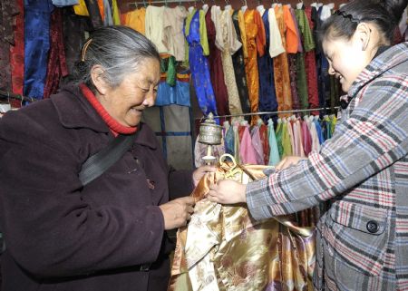 A senior woman of Tibetan ethnic group selects traditional clothes of Tibetan ethnic group at a shop in Lhasa, capital of southwest China's Tibet Autonomous Region, on February 18, 2009. Traditional clothes of Tibetan ethnic group are popular among people of Tibetan ethnic group as Tibetan New Year, which falls on February 25 this year, is coming.