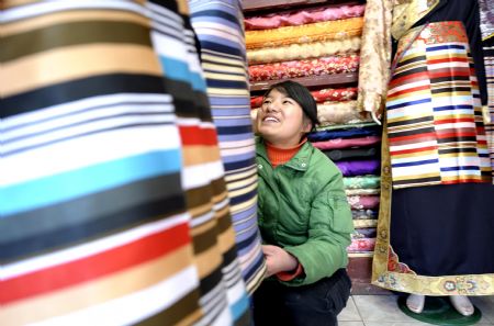 A young lady of Tibetan ethnic group selects traditional clothes of Tibetan ethnic group at a shop in Lhasa, capital of southwest China's Tibet Autonomous Region, on February 18, 2009. Traditional clothes of Tibetan ethnic group are popular among people of Tibetan ethnic group as Tibetan New Year, which falls on February 25 this year, is coming.