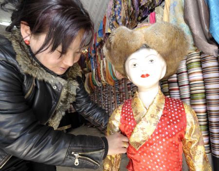 A shopowner shows a traditional children's clothes of Tibetan ethnic group at her shop in Lhasa, capital of southwest China's Tibet Autonomous Region, on February 18, 2009. Traditional clothes of Tibetan ethnic group are popular among people of Tibetan ethnic group as Tibetan New Year, which falls on February 25 this year, is coming. 