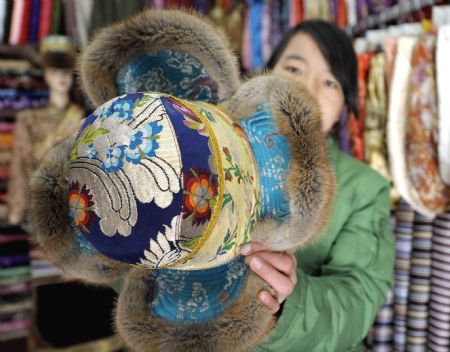 A shopowner shows a traditional hat of Tibetan ethnic group at her shop in Lhasa, capital of southwest China's Tibet Autonomous Region, on February 18, 2009. Traditional clothes of Tibetan ethnic group are popular among people of Tibetan ethnic group as Tibetan New Year, which falls on February 25 this year, is coming. 