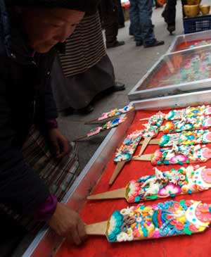 A woman sells color plates, which are necessary tools for the Tibetan New Year, at a market in Lhasa, capital of southwest China's Tibet Autonomous Region, on February 22, 2009. 