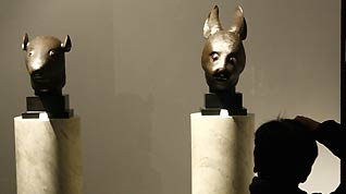 A photographer takes a picture of the Chinese bronze rat head and rabbit head sculptures displayed on the preview of the auction of Yves Saint Laurent and Pierre Berge's art collection at the Grand Palais in Paris, France, on February 21, 2009.