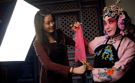 A lady (R), with her dressing and face-painting in Beijing Opera style, poses for pictures at a studio in the provincial city of Jinan, east China's Shandong Province, on February 25, 2009. Costume and face-painting in Beijing Opera style attracted more and more fans and youth to the studio for taking a series of memorial pictures.