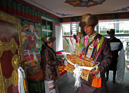 A local villager holds Qiema, a two-tier rectangular wooden box containing roasted barley and food prepared with butter, parched barley meal and sugar, to welcome guests in Gaba Village in east Lhasa, capital of southwest China's Tibet Autonomous Region, on February 25, 2009. 