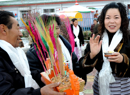 A Tibetan presents Qiema, a two-tier rectangular wooden box containing roasted barley, and highland barley drink to his friend Wei Kexiu from Chongqing in Lhasa, capital of southwest China's Tibet Autonomous Region, on February 25, 2009. 