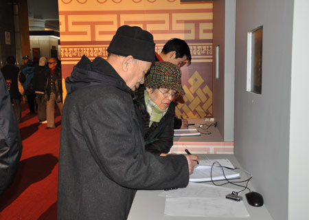 Zhang Chengzhou leaves message on a notebook as his wife looks on after visiting an exhibition marking the 50th anniversary of the Democratic Reform in Tibet Autonomous Region in Beijing, on February 25, 2009. 