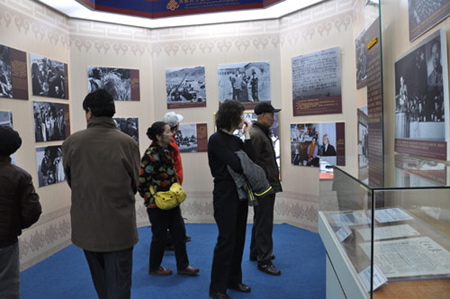 Photo taken on February 26, 2009 shows visitors watch pictures recording the crack-down on the armed rebellion staged by a small number of reactionary monks, serfowners and officials in 1956 at the 50th Anniversary of Exhibition of Democratic Reforms in Tibet.