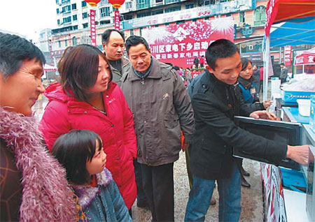 A shop clerk demonstrates the functions of a microwave oven to potential customers from the rural areas in Yongchuan, Chongqing.