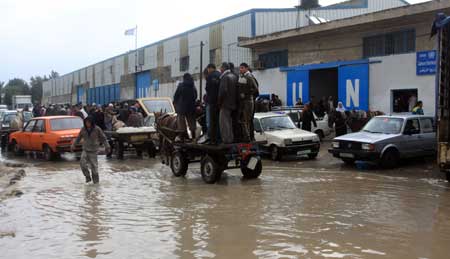 Palestanian people walk through the flooded street after a rainstorm in Gaza City, on March 1, 2009. 