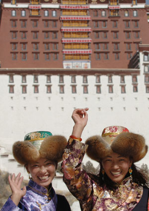 Two women pose for photos in front of the Potala Palace in Lhasa, capital of southwest China's Tibet Autonomous Region, on February 11, 2008. 