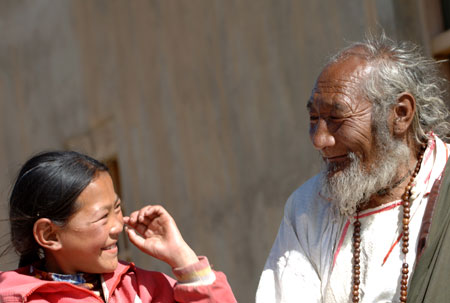 An old man and his granddaughter share a happy moment in Nagqu Town, southwest China's Tibet Autonomous Region, on June 13, 2006.