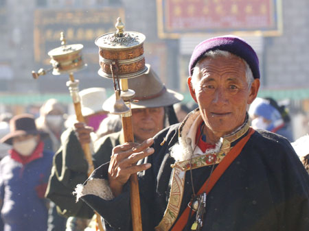 Buddhism followers of the Tibetan ethnic group spin their prayer wheels to spread spiritual blessings to all sentient beings and invoke good karma in their next life when walking on a street in Lhasa, capital of southwest China's Tibet Autonomous Region, in November 2007. 