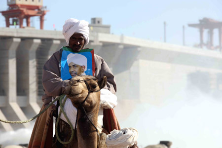 A man holding a portrait of Sudanese President Omar al-Beshir (R2, front) attends a ceremony at Merowe Dam in Merowe, Sudan, on March 3, 2009. 
