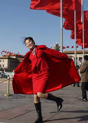 An attendant poses for photos in front of the Great Hall of the People in Beijing, capital of China, on March 5, 2009. The Second Session of the 11th National People's Congress (NPC) opened on Thursday. 