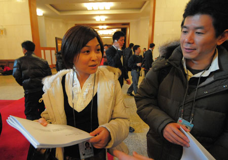 Two Japanese journalists get the documents of the Second Session of the 11th National People's Congress (NPC) before the opening of the session at the Great Hall of the People in Beijing, capital of China, on March 5, 2009.